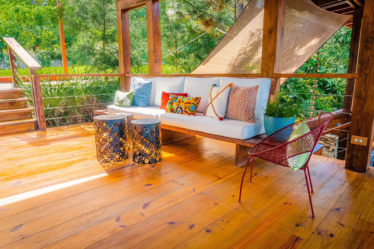 Terraza de madera con muebles rodeada de árboles en Quintas del Bosque